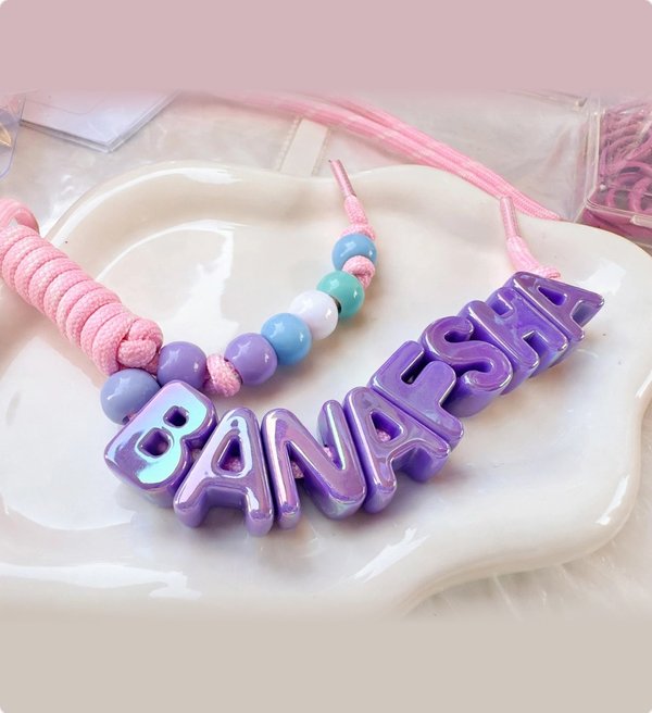 Violet letter keychain spelling BANAFSHA on blush pink cord