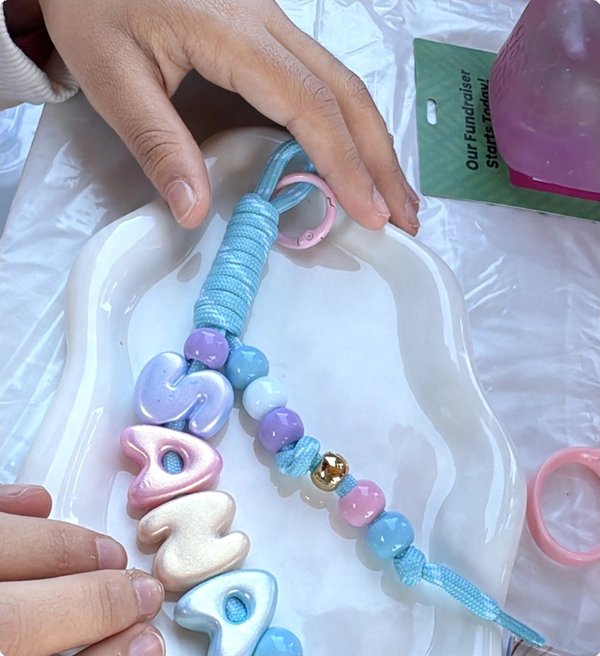 Baby blue keychain spelling SANA on a cloud tray