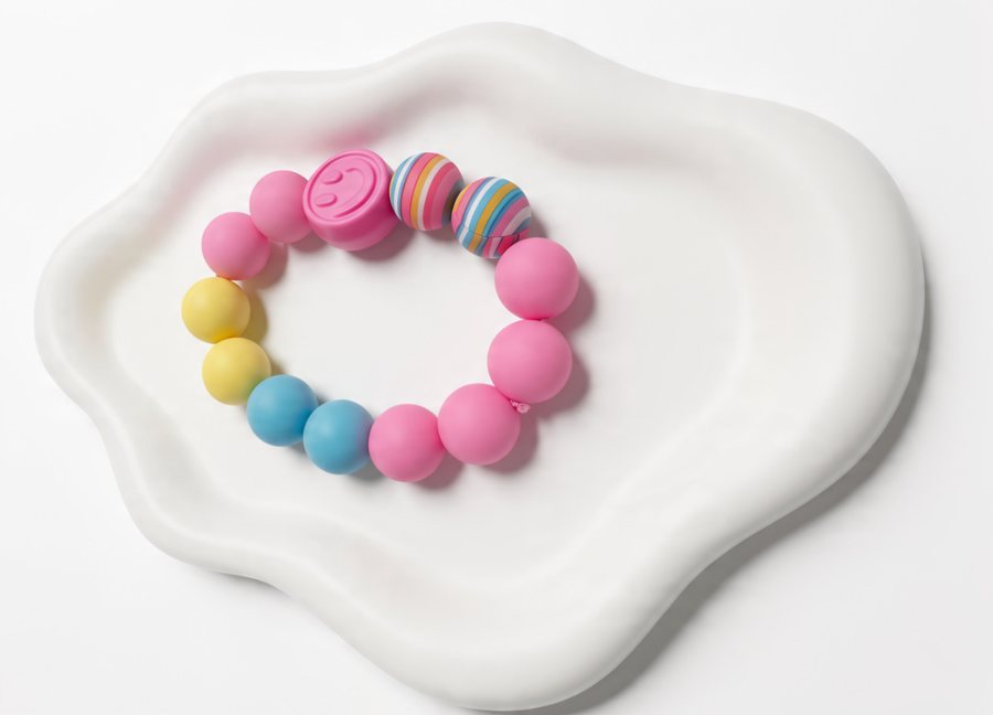 Pink, yellow and blue silicone bracelet with a smiley bead and striped beads