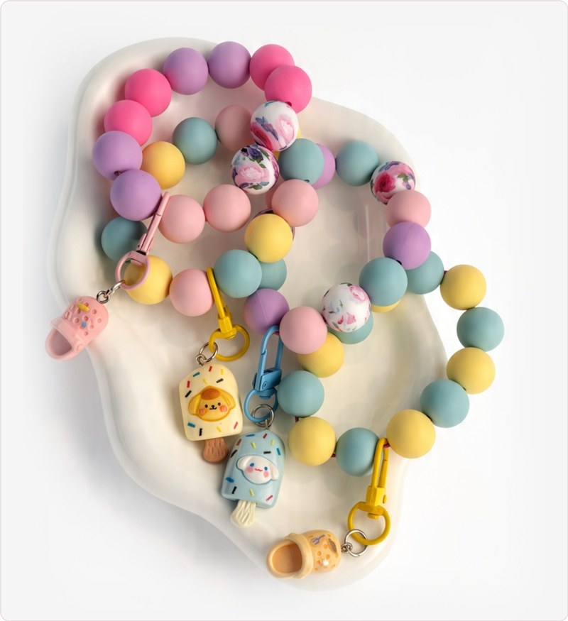 Four pastel silicone wristlet keychains with floral beads, mini clog charms and ice pop charms
